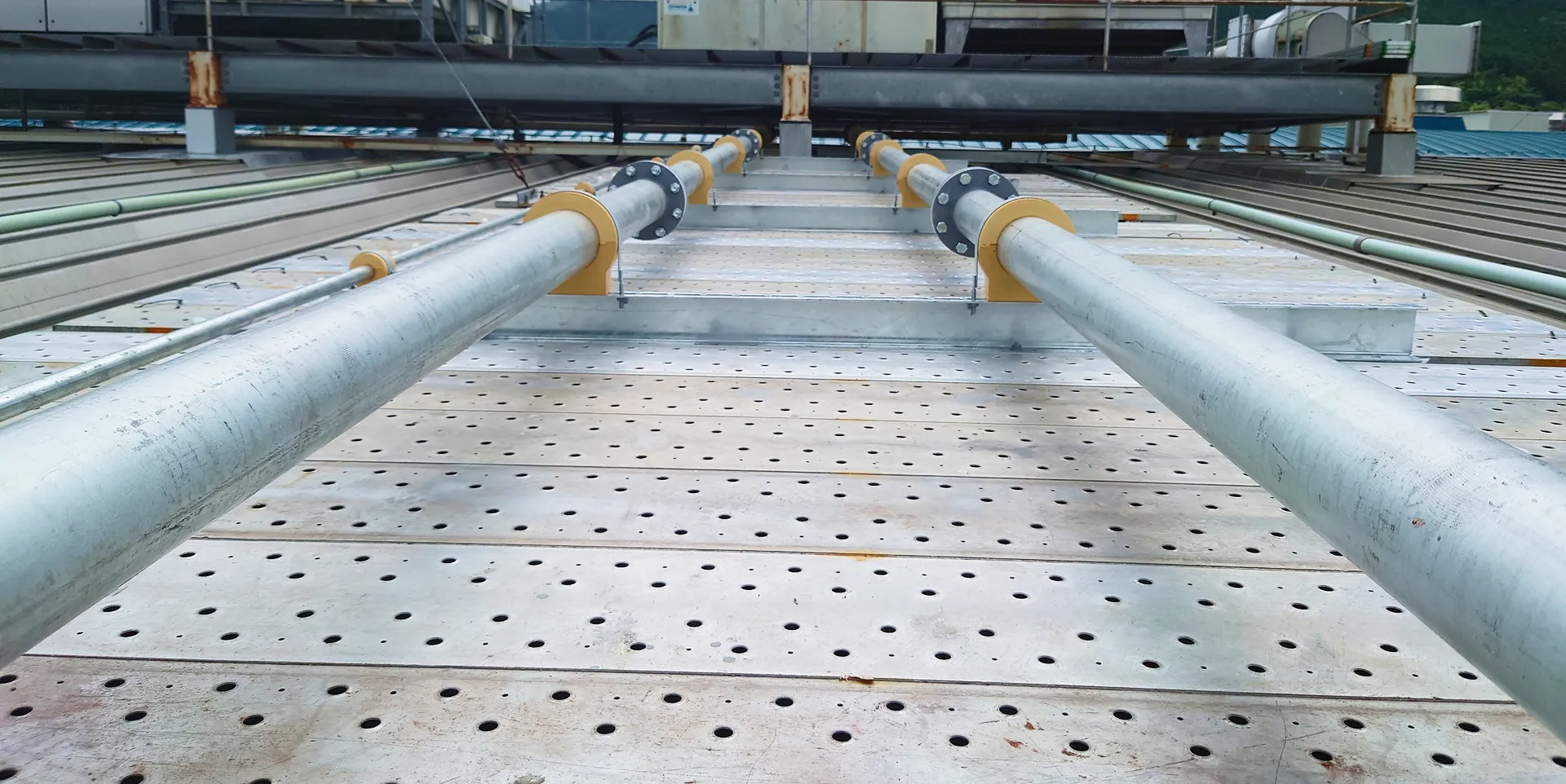 穴の開いた金属パネルの上に取り付けられた、金属製のパイプ二本のクローズアップ写真。